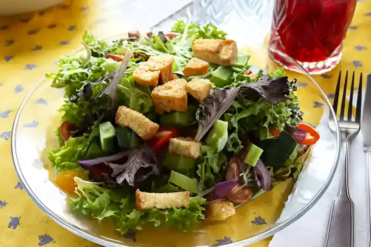 Fresh house salad with croutons and mixed greens on a glass plate.