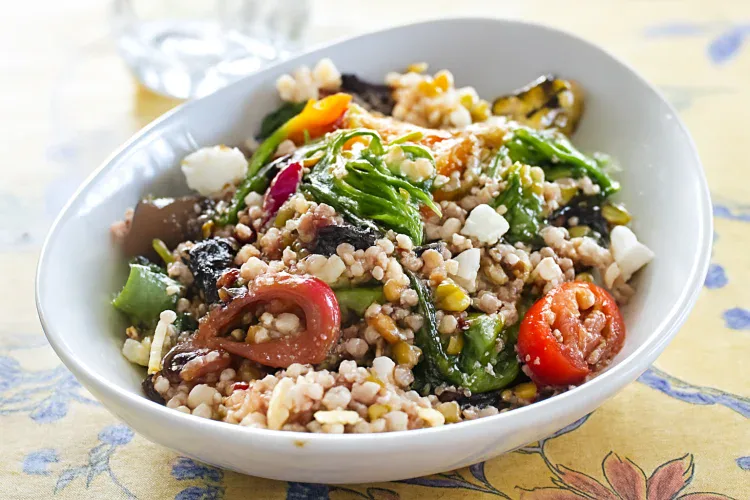 Colorful Mediterranean grain bowl with vegetables and feta cheese.