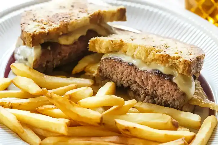 Delicious Patty Melt with melted cheese and grilled bread served with fries.