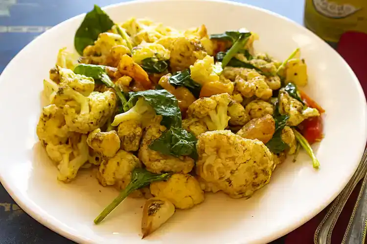 Roasted cauliflower with herbs and garlic on a white plate.