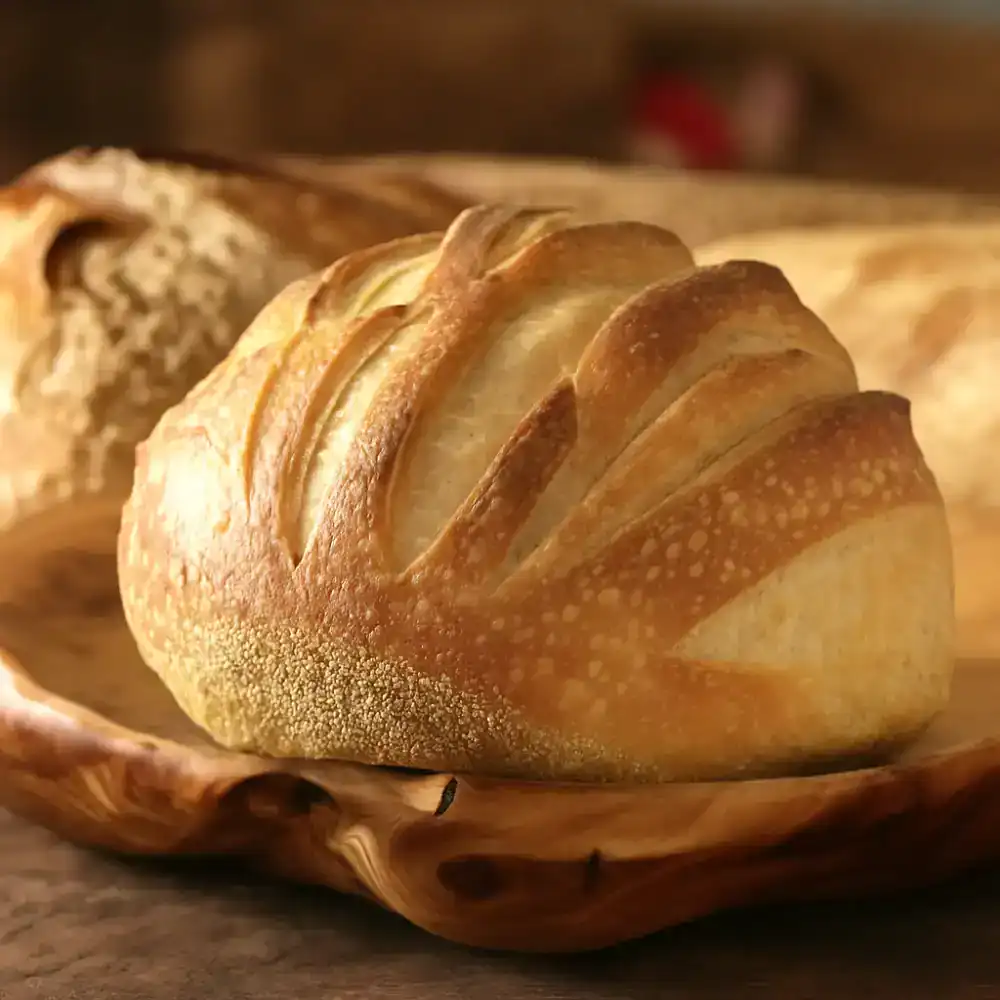 Artisan sourdough bread with scoring on a wooden board.