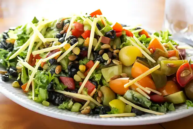 Colorful Southwest Salad with vegetables, cheese, and seeds on a white plate.