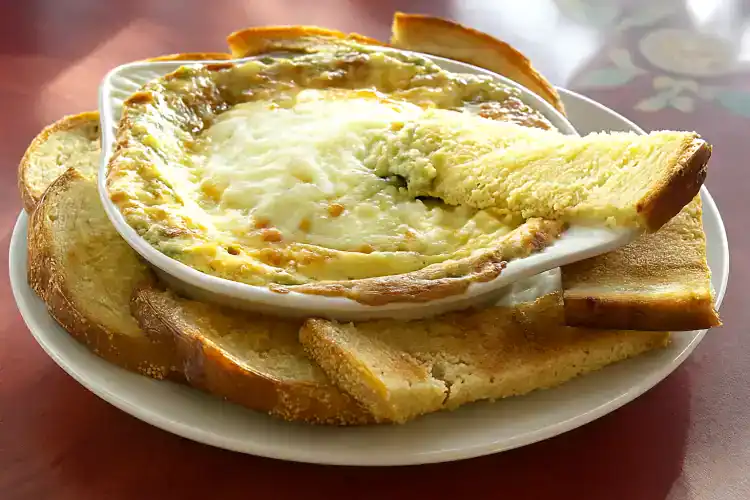 Creamy spinach and artichoke dip served with toasted bread slices.