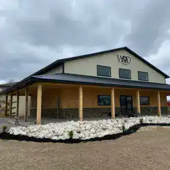 WaterDog Outfitters store with wooden porch and stone foundation under cloudy sky.
