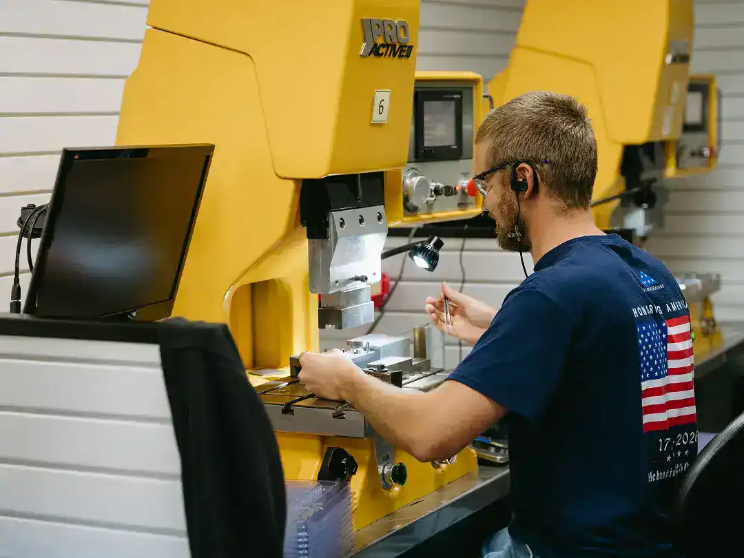 Manufacturing technician operating industrial machinery in a factory setting.
