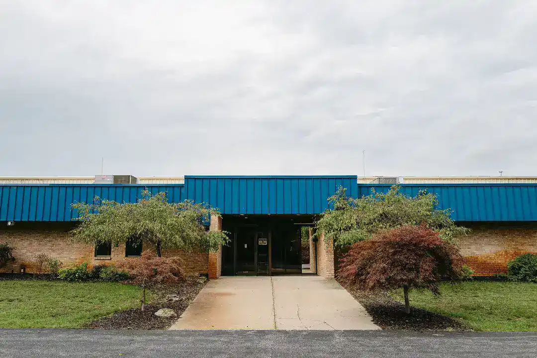 Active Manufacturing facility with blue roof and landscaped front yard.