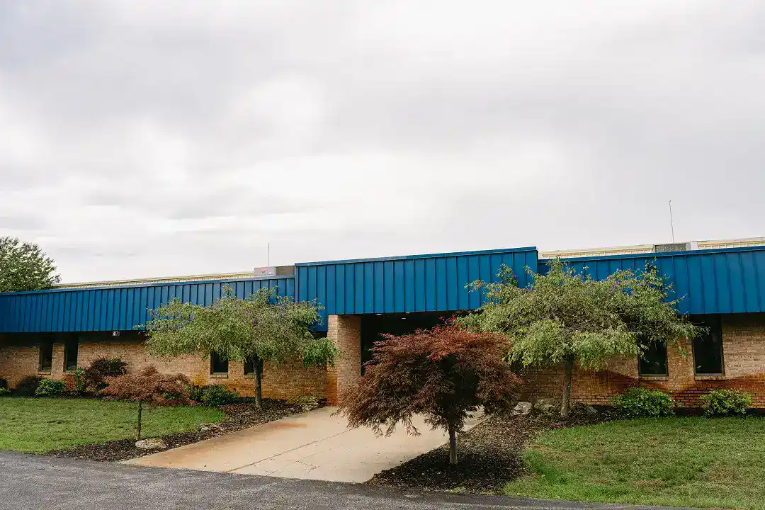 Active Manufacturing building with blue roof and landscaped front yard.