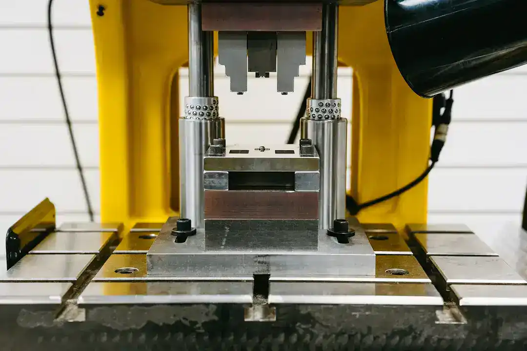 Industrial manufacturing machine with metal components and yellow frame.