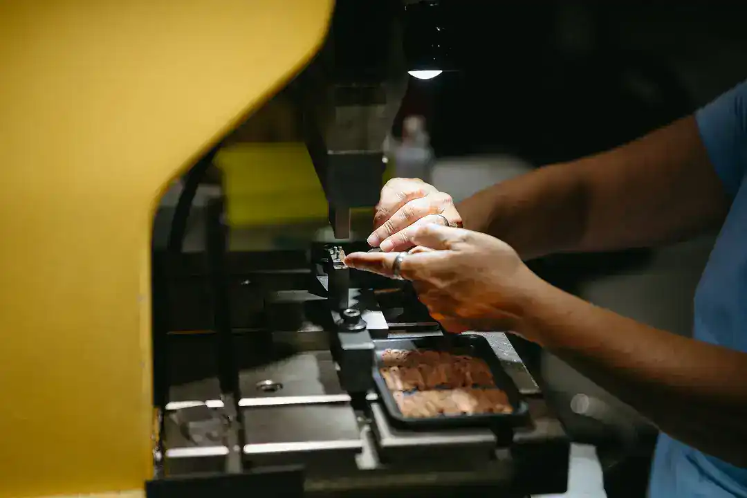 Manufacturing process with precision machinery and worker handling metal parts.
