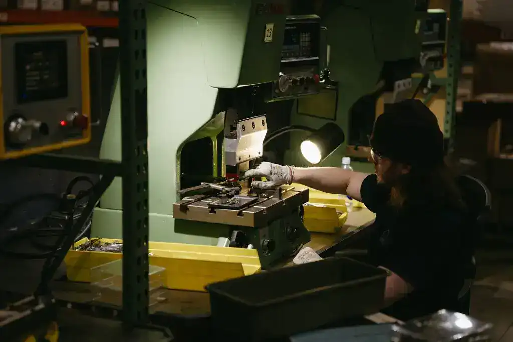 Manufacturing technician working on precision machinery in a factory setting.