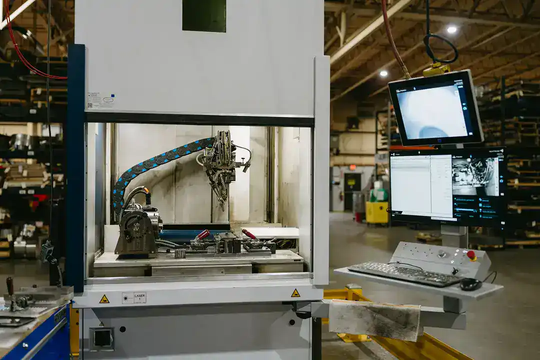 Industrial manufacturing robot in a factory setting with computer control system.