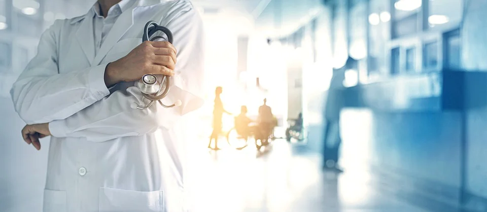 doctor holding stethoscope with hospital staff in background