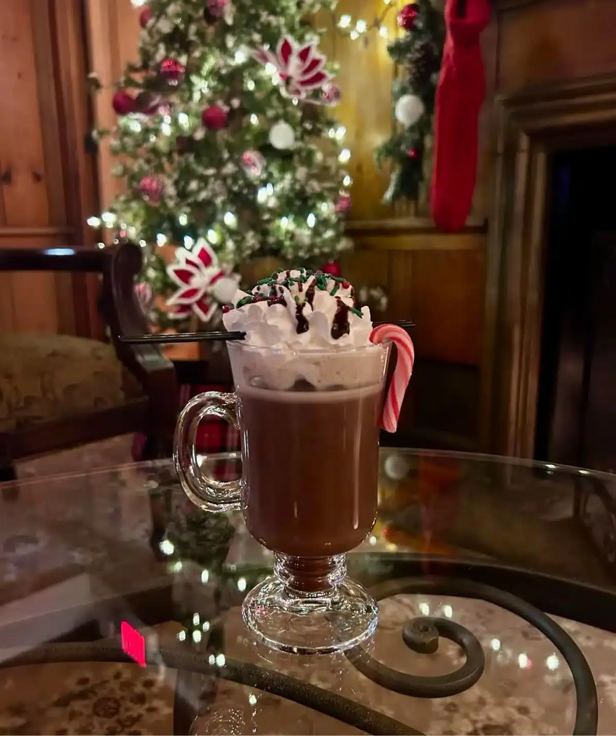 Warm holiday drink with whipped cream and candy cane in festive setting.