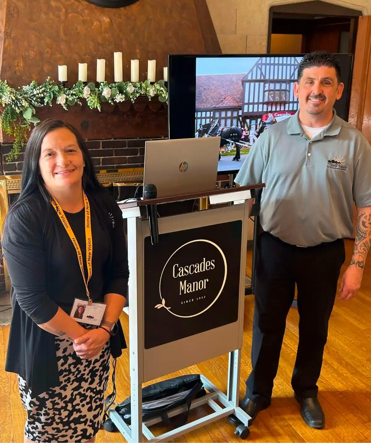 Cascades Manor staff at event registration desk with display screen.