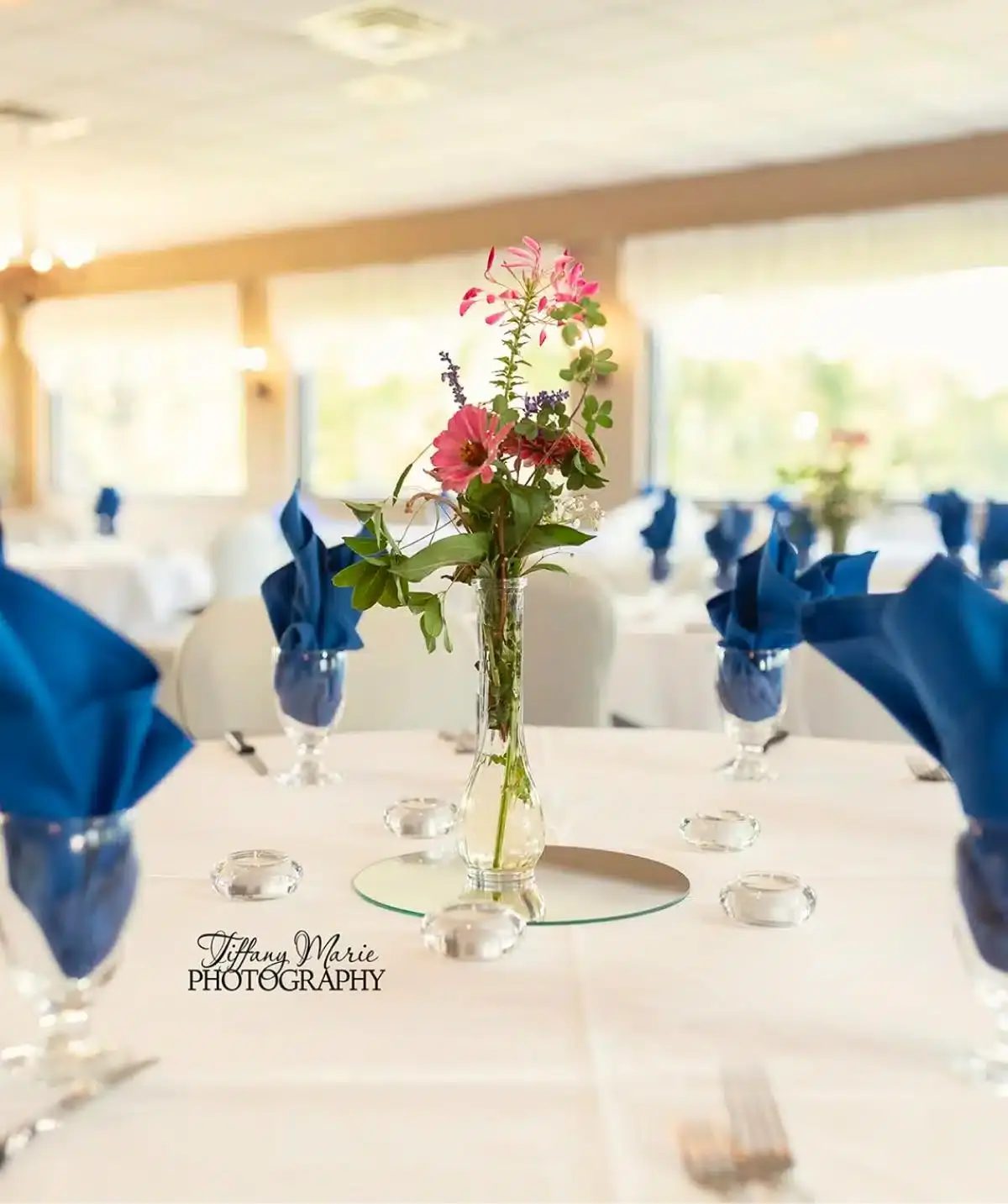 Elegant event table with floral centerpiece and blue napkins at Cascades Manor.
