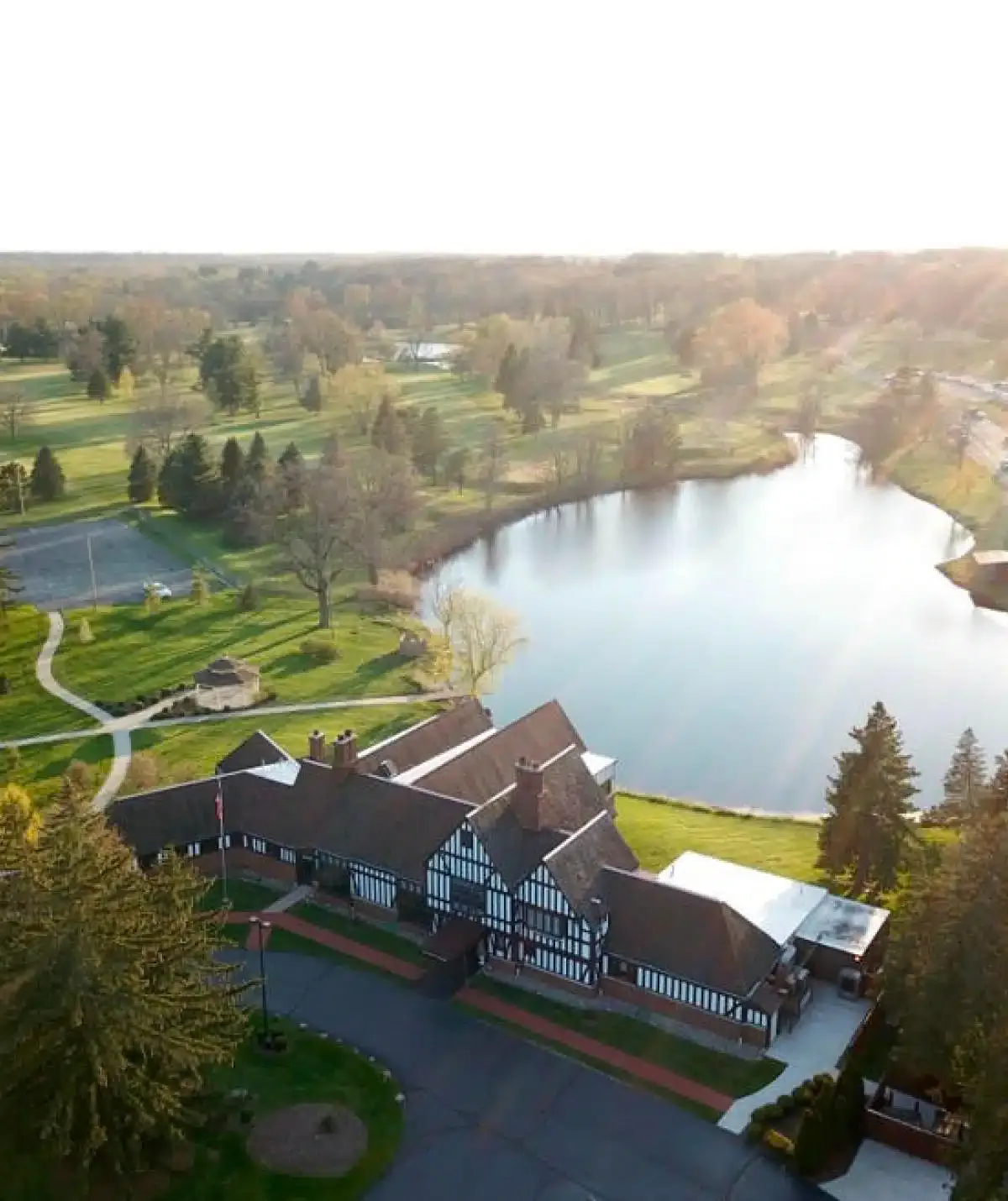 Aerial view of Cascades Manor with lush greenery, a pond, and surrounding landscape.
