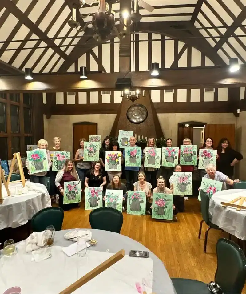 Group of people holding their floral paintings at Cascades Manor event.