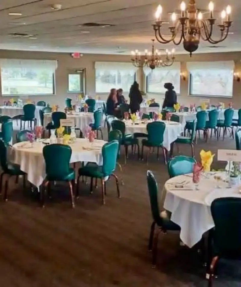 Banquet hall with round tables, colorful napkins, and chandeliers at Cascades Manor.