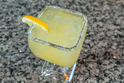 Lemon Margarita with salted rim and lemon wedge on a glass.