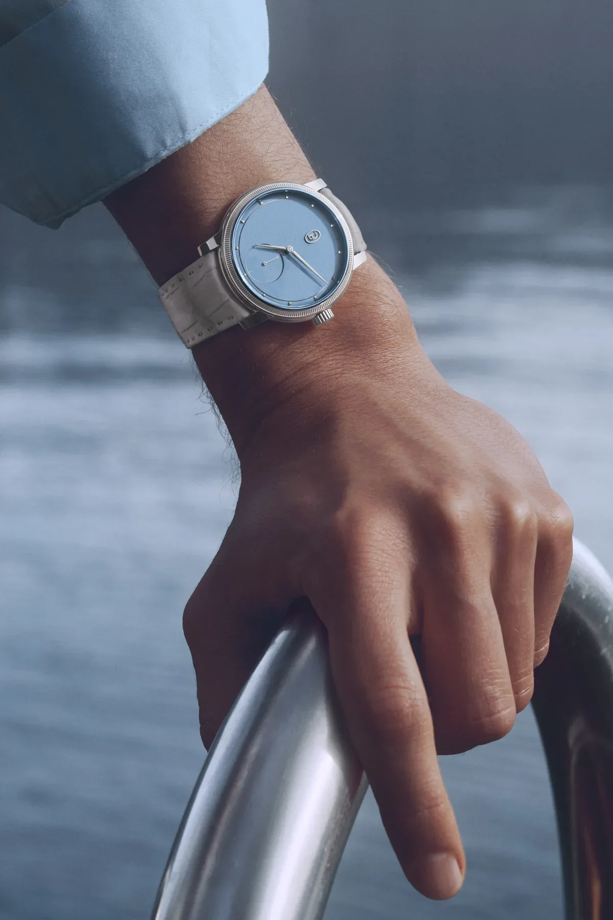 The Toric Petite Seconde Morning Blue worn on the wrist, a hand resting on a boat railing
