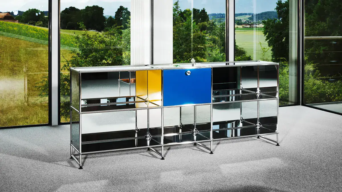 Mirrored USM Haller sideboard with yellow and blue panels, made to accompany the Zenith DEFY Chronograph USM TimeForArt Unique Piece, in a glass-walled room