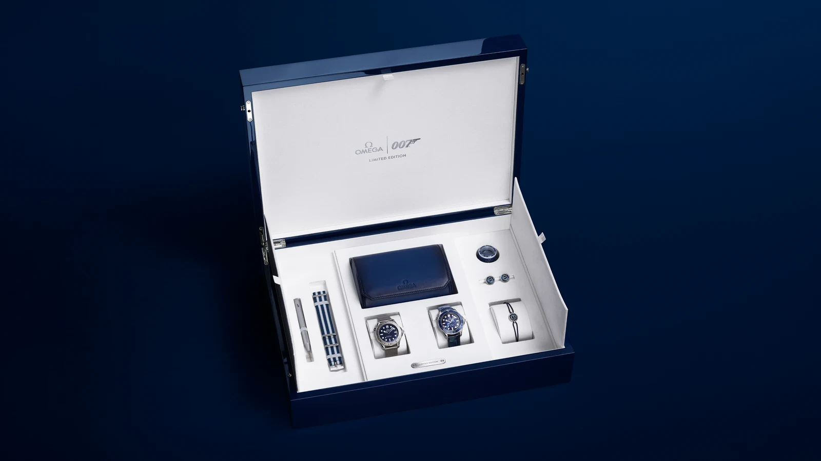 The James Bond limited-edition set from the Omega Seamaster James Bond Spectre collection in its open blue box: the steel model on a mesh bracelet, the platinum-gold model on a dark blue leather strap, a NATO strap, cufflinks, cord bracelet and travel pouch