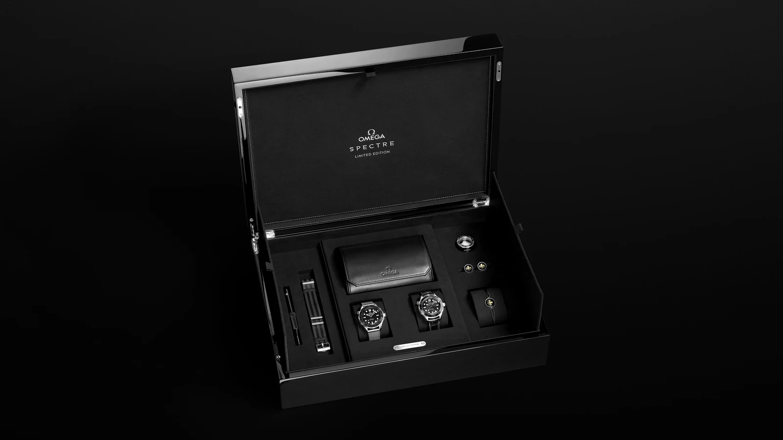 The Spectre limited-edition set from the Omega Seamaster James Bond Spectre collection in its open black box: the steel model on a mesh bracelet, the platinum-gold model on a black leather strap, a NATO strap, cufflinks, cord bracelet and travel pouch