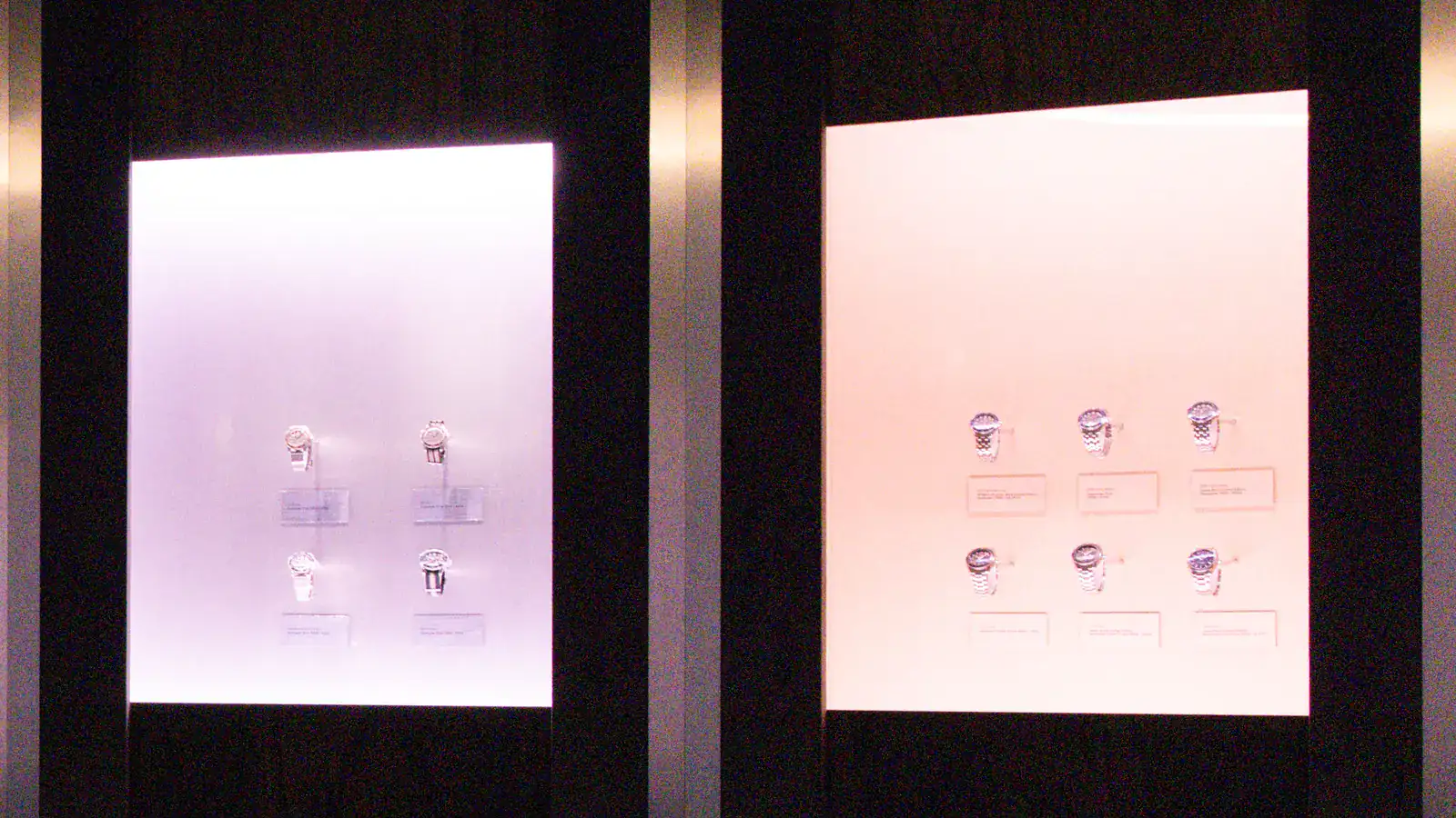 Two lit display cases in the watch room of the Omega Seamaster James Bond Spectre exhibition in Glendale; the case on the right holds six Seamasters from the OMEGA Museum with placards