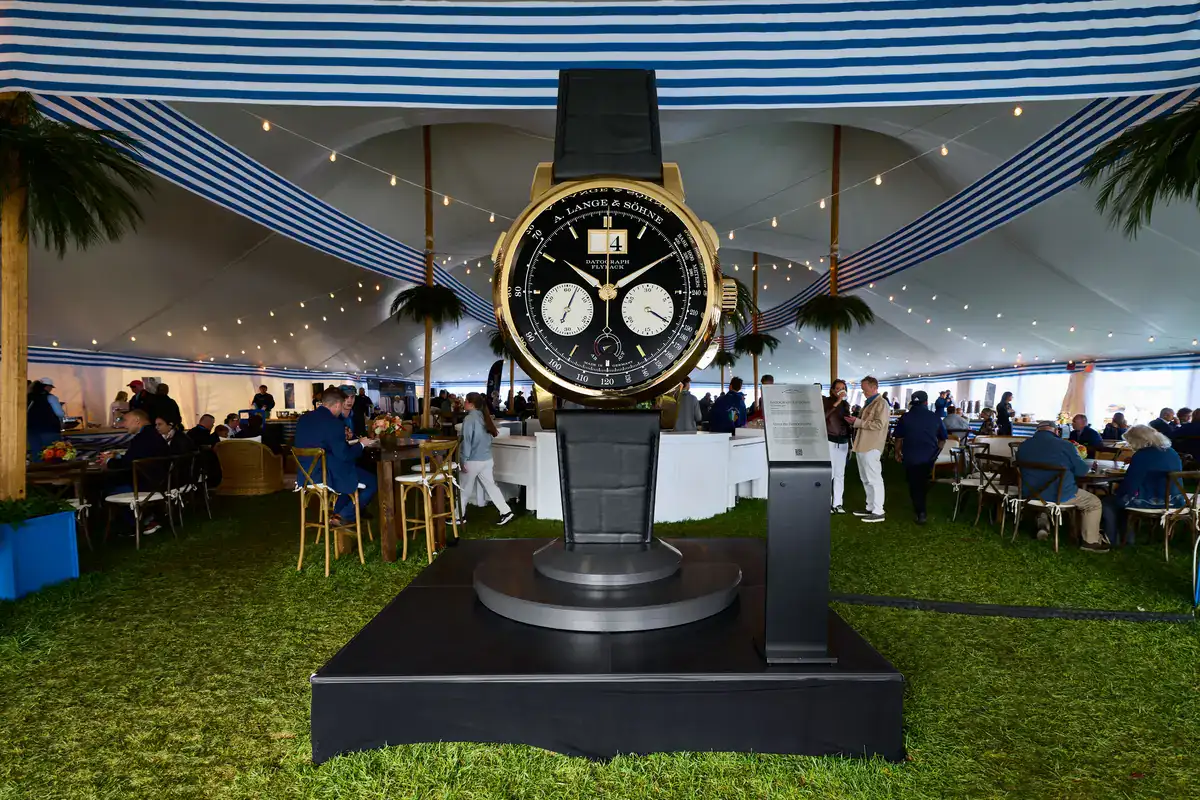 Oversized gold A. Lange & Söhne DATOGRAPH FLYBACK display with a black dial under a blue-and-white striped tent at the Audrain Newport Concours d'Elegance 2026