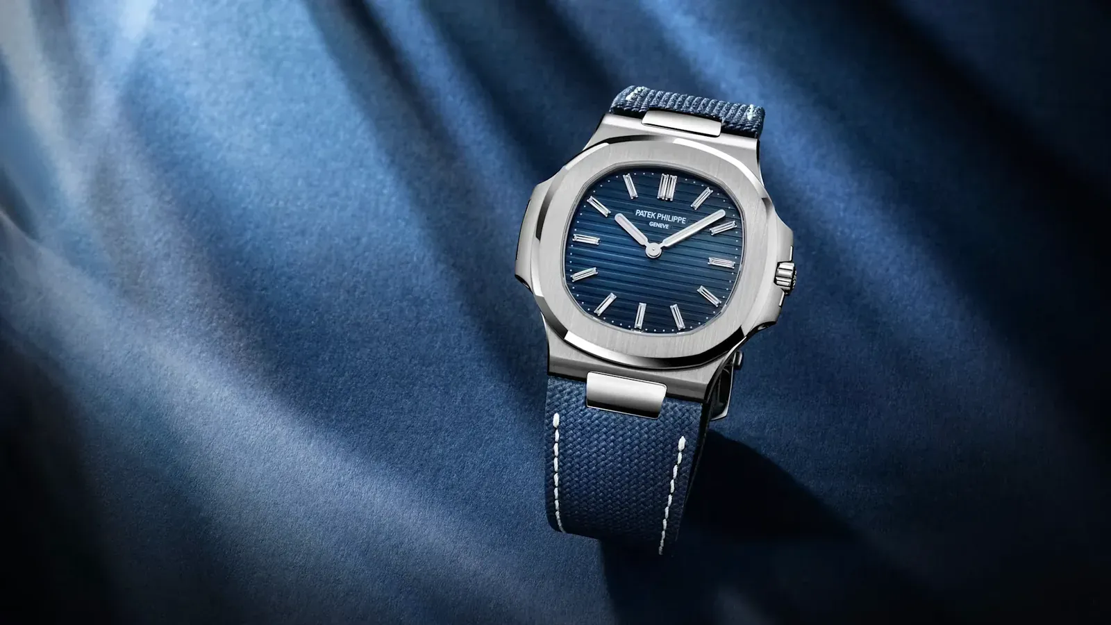 Messi Patek Philippe Nautilus 5810G-001 in white gold lying on blue fabric, sunburst blue dial and navy strap