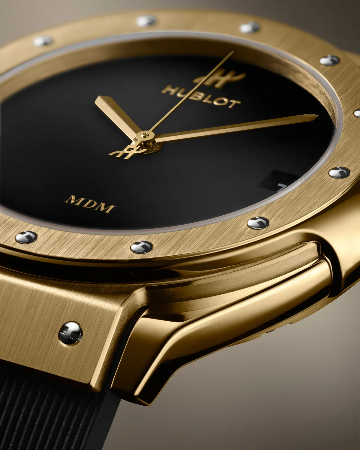 Close-up of the Hublot Classic Fusion Tributo yellow gold dial with gold MDM pad print at 6 o'clock and H-shaped bezel screws