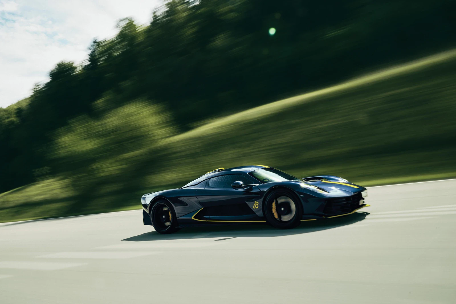 The Aston Martin Valhalla supercar at speed on a country road, the car behind the Breitling Super Chronomat Aston Martin Valhalla program