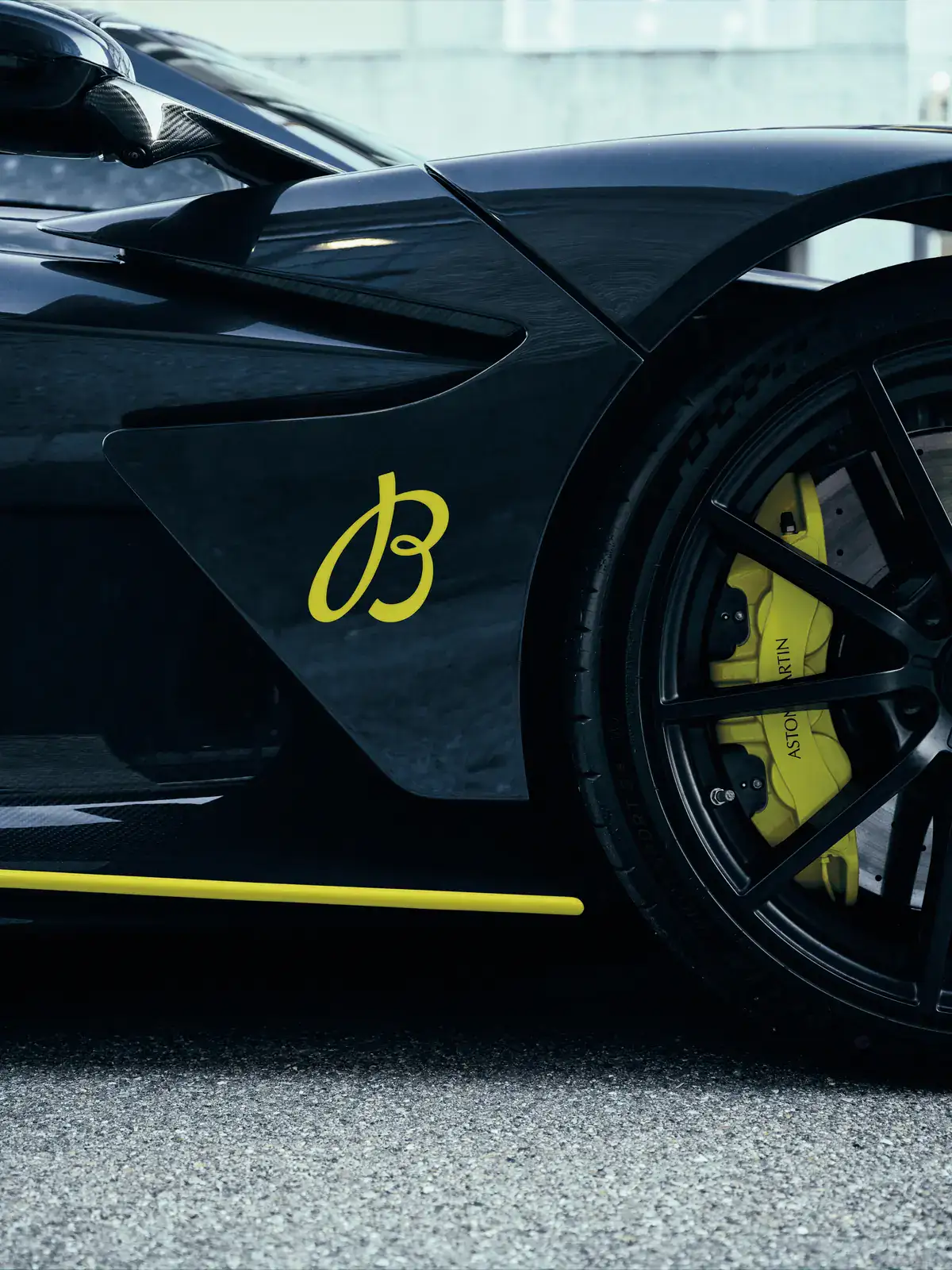 Aston Martin Valhalla with a yellow Breitling B script on its flank and lime brake calipers, part of the Breitling Super Chronomat Aston Martin Valhalla story