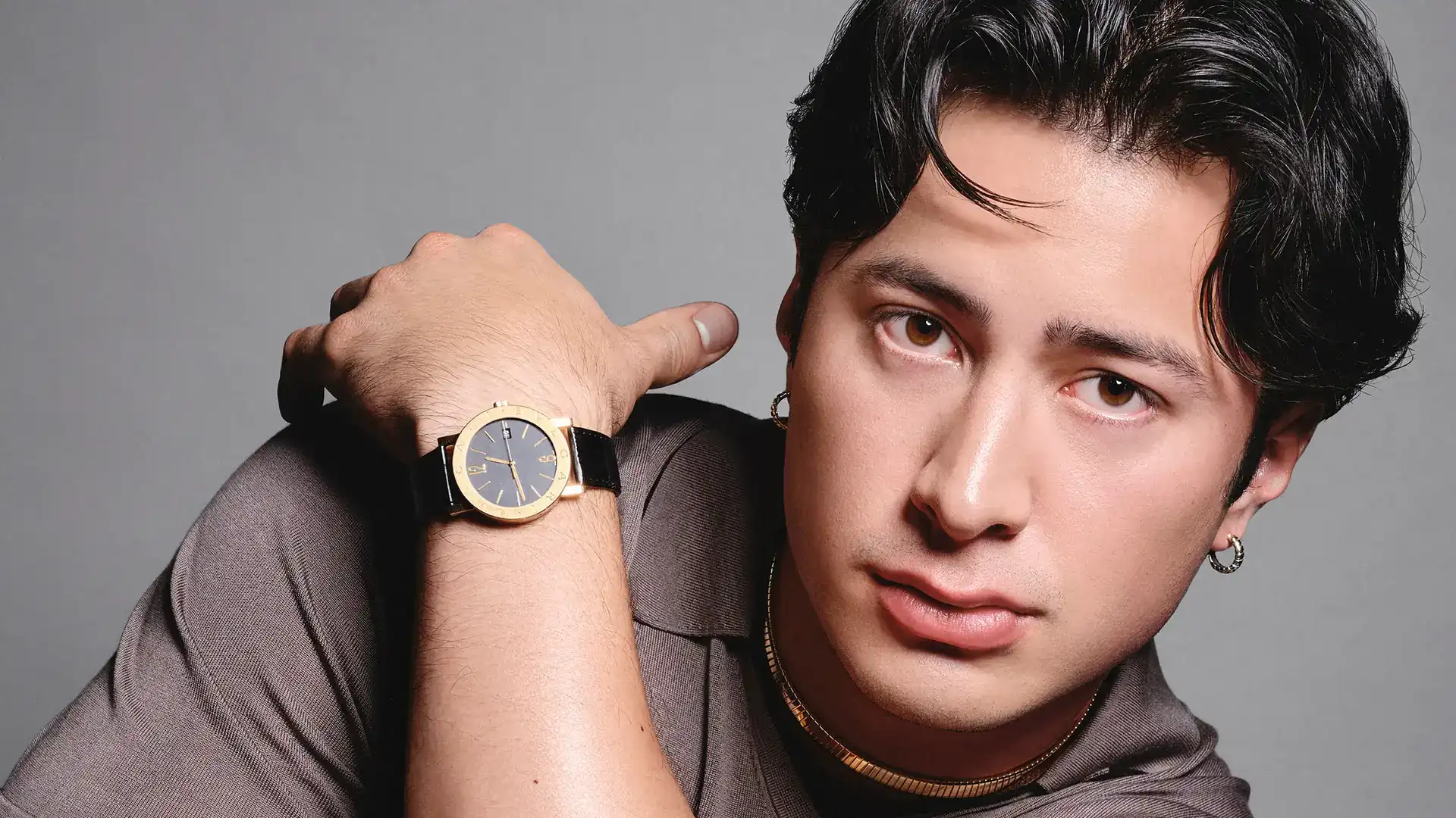 Hudson Williams Bulgari ambassador portrait wearing a gold watch on a black strap and a gold chain