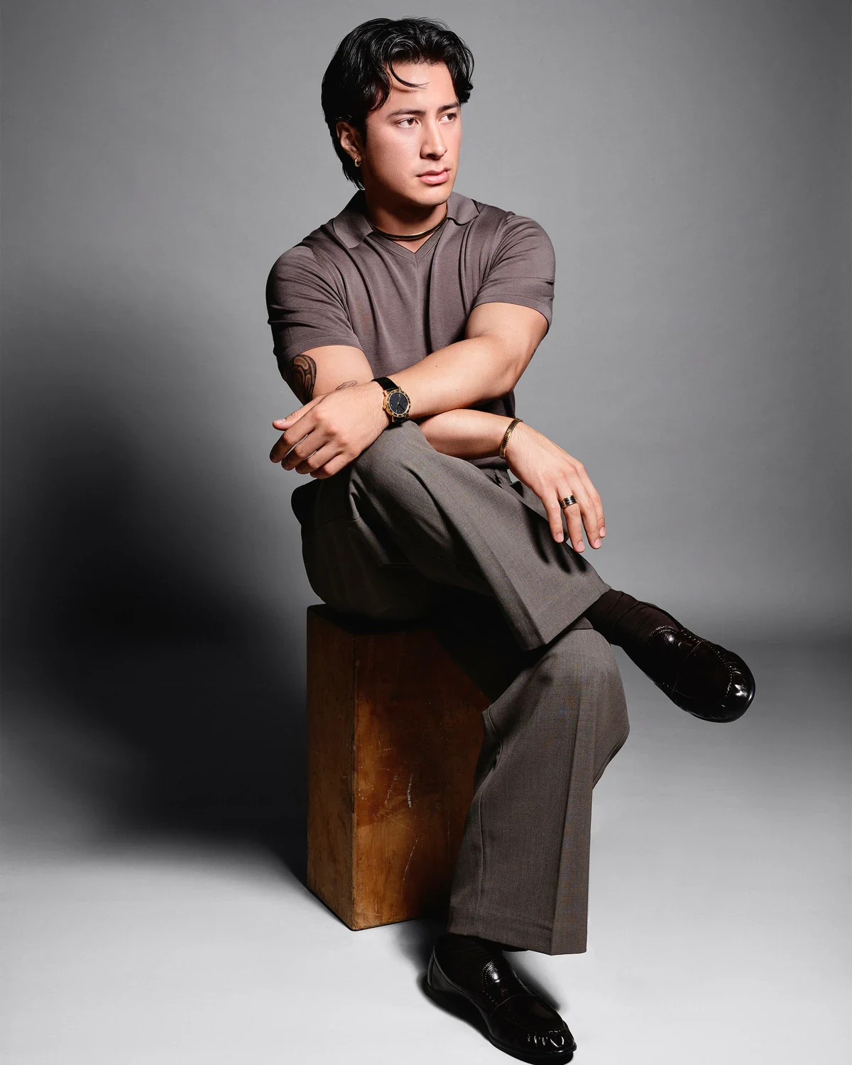 Hudson Williams Bulgari ambassador Hudson Williams seated on a wooden block against a pale gray backdrop