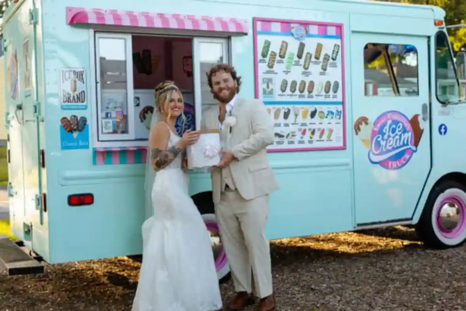 Ice cream truck with colorful signage and two people in wedding attire.