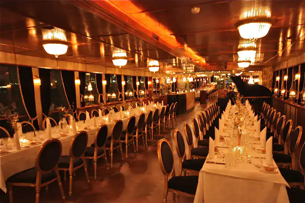 A luxurious restaurant with long tables set for dinner. Soft lighting and elegant decor create a sophisticated ambiance.