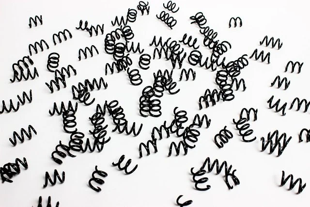Black spiral paper clips scattered randomly on white background, creative stationery for office or craft projects, shaped in the form of small coils, minimalistic and modern work supplies, top view image.