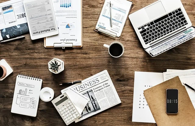 Business workspace with financial documents, laptop, calculator, and smartphone for professional productivity and financial analysis in an office setting.