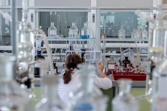 Laboratory scientist conducting chemical experiments with glassware in a high-tech research lab.