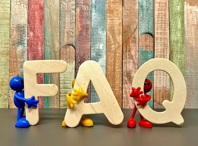 F A Q wooden letters with colourful small characters, set against a rustic wooden background.