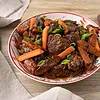 Beef and carrot stew served in a deep, patterned plate