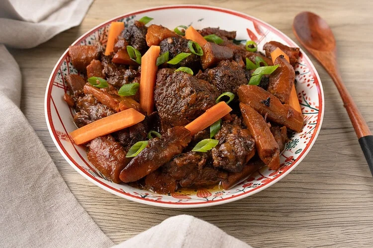 Beef and carrot stew served in a deep, patterned plate