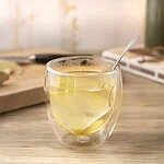 Infusion gingembre citron dans un verre à double paroi, avec une rondelle de citron et une cuillère