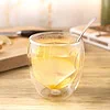Infusion gingembre citron dans un verre à double paroi, avec une rondelle de citron et une cuillère, sur un plan de travail en bois clair
