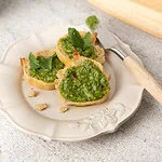 Tartines de pain grillé garnies de pesto de roquette vert vif, avec des feuilles de roquette et des noix de cajou