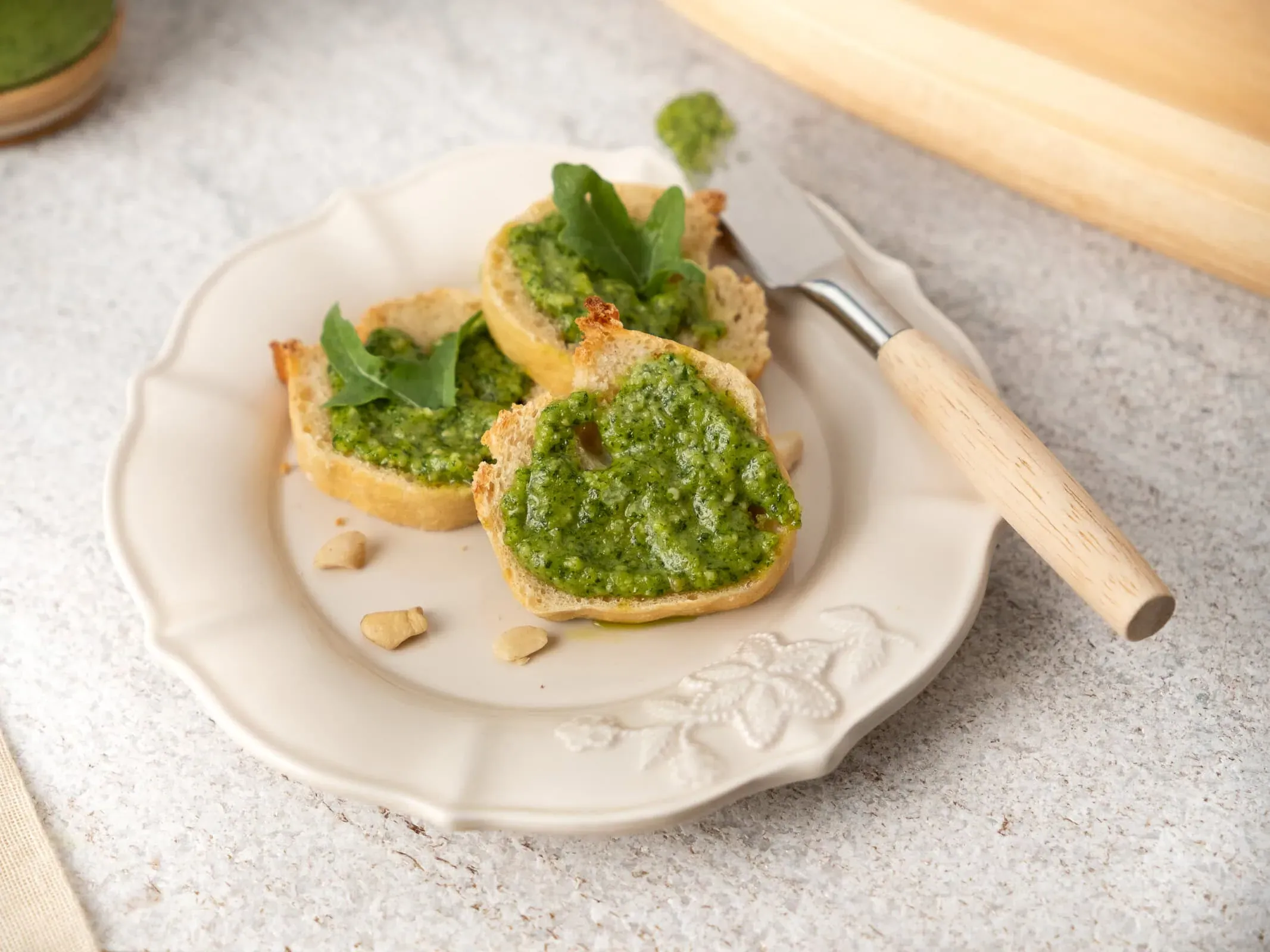 Tartines de pain grillé garnies de pesto de roquette vert vif, avec des feuilles de roquette et des noix de cajou