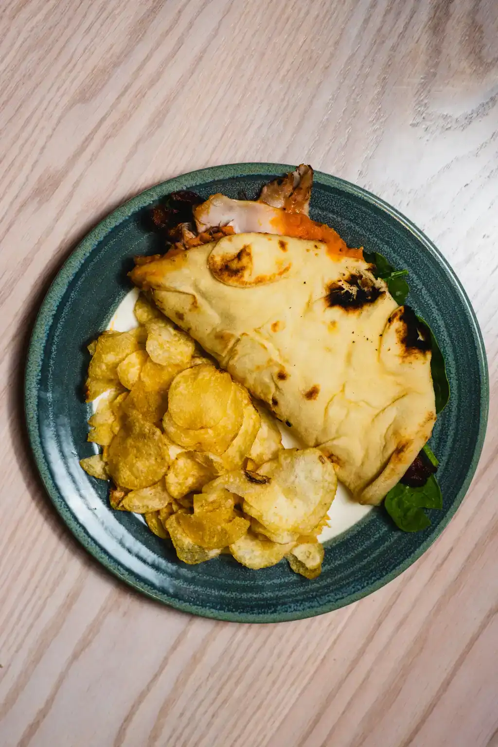 Traditional fish and chips served with a side of greens on a green plate.