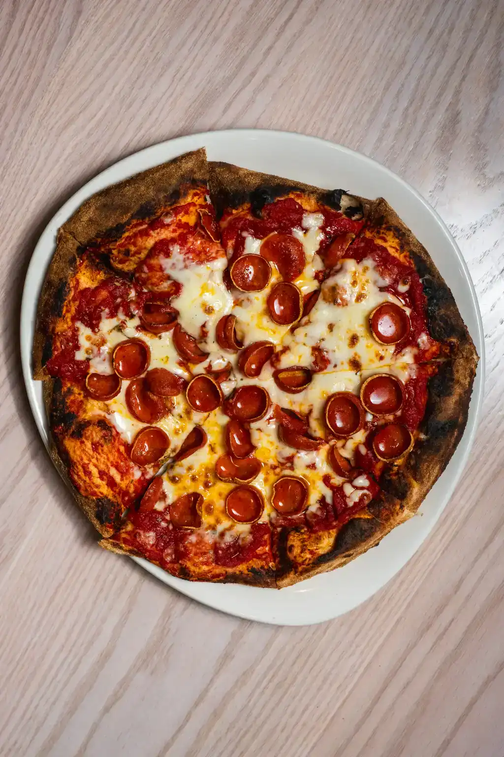 Freshly baked pepperoni pizza with melted cheese on a wooden table.