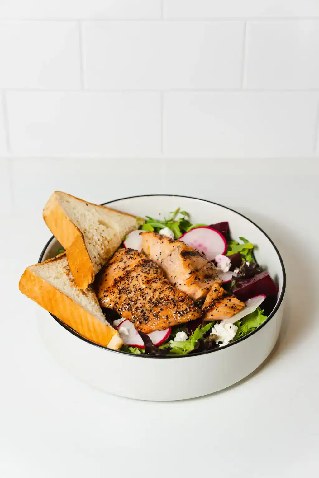 Fresh grilled salmon salad with mixed greens and toasted bread slices.